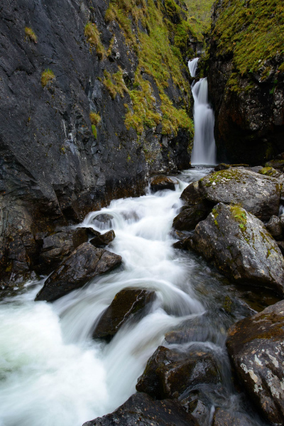 Ein Gebirgsbach fließt über Felsen zu einem Wasserfall in Norwegen.