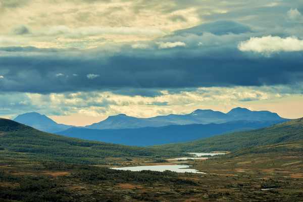 Weite Landschaft in Norwegen mit Hügeln und dramatischem Himmel.